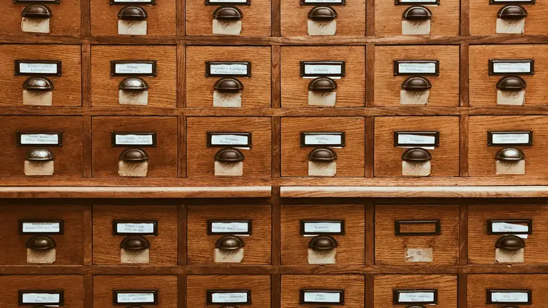 Rows of labelled wooden card-catalogue drawers with brass pulls.